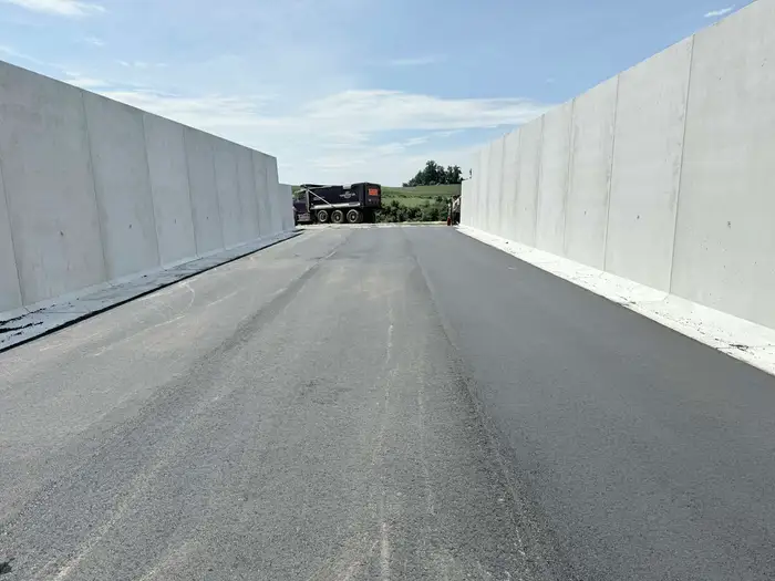 Newly surfaced access lane running between poured concrete retaining walls