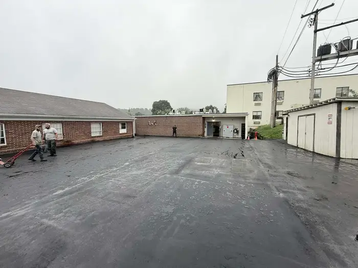 Resurfaced commercial parking area behind a brick office building on an overcast day
