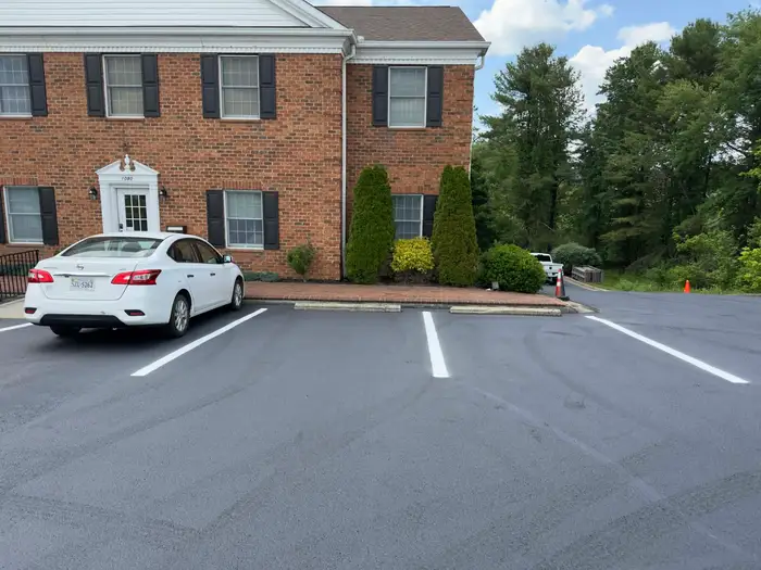 Fresh sealcoat and crisp white stall markings at a brick office building