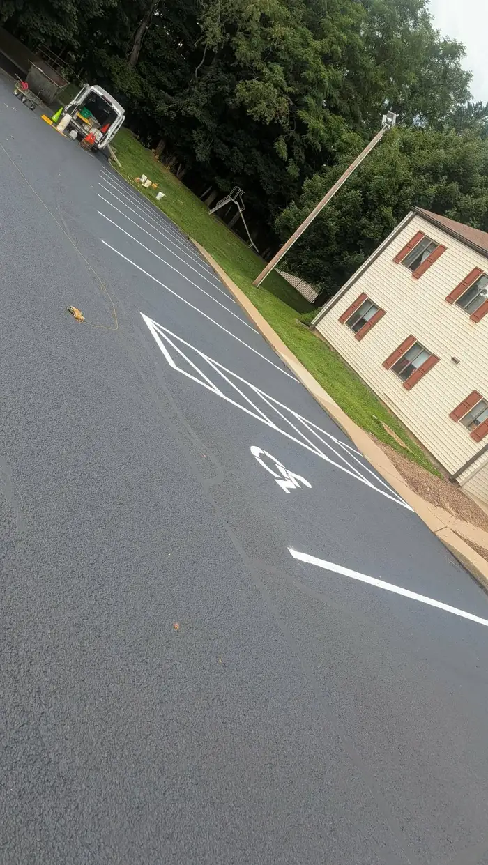 Freshly sealcoated lot with new white stalls and a diagonally hatched access aisle