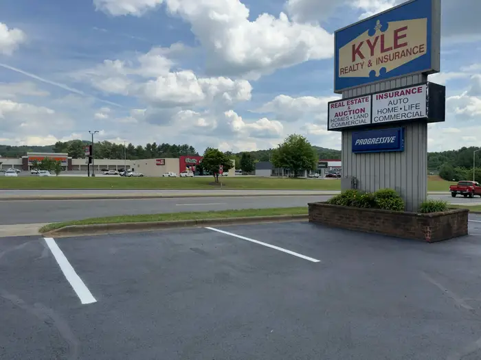 Sealed and re-striped lot at a roadside office, with a retail strip across the four lane highway