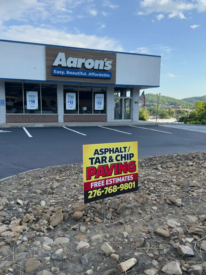 Newly sealed and striped retail storefront lot, with a Lines by JD paving sign in the stone border