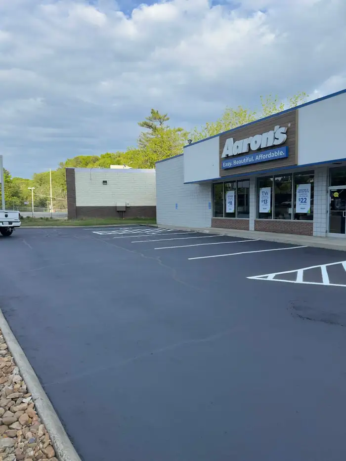 Wide view of a resealed retail lot with fresh white stalls and a hatched accessible aisle