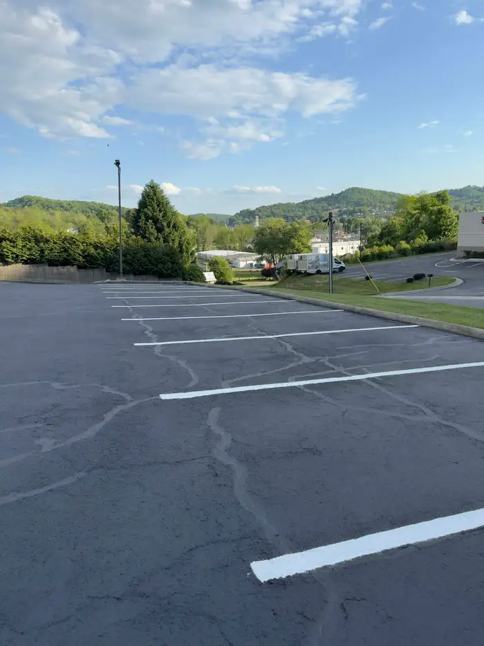 Resealed hilltop parking lot with crack sealed seams showing through, overlooking a valley