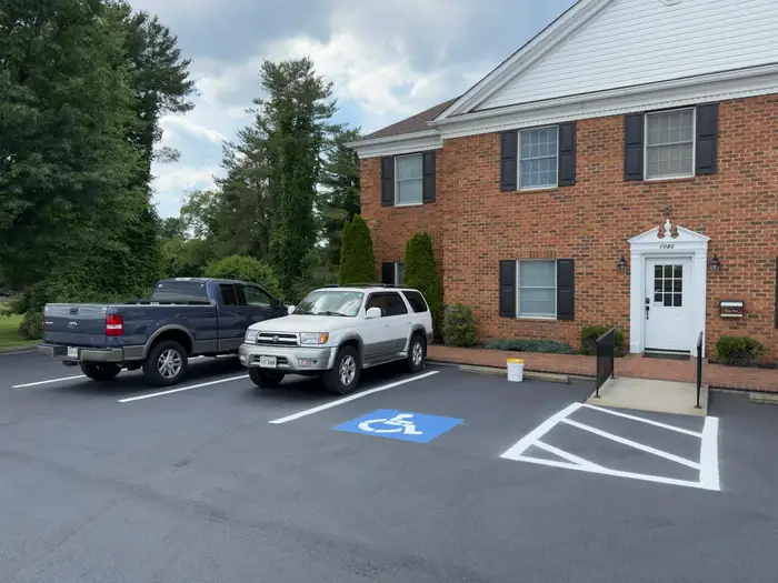 Accessible parking stall marked with a blue wheelchair symbol beside a hatched access aisle at an office